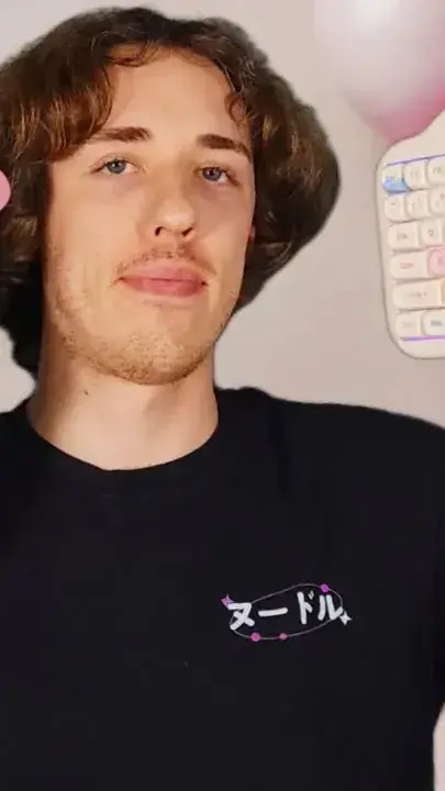 Tech reviewer in a black T-shirt, with the edge of a pastel keyboard in frame beside him