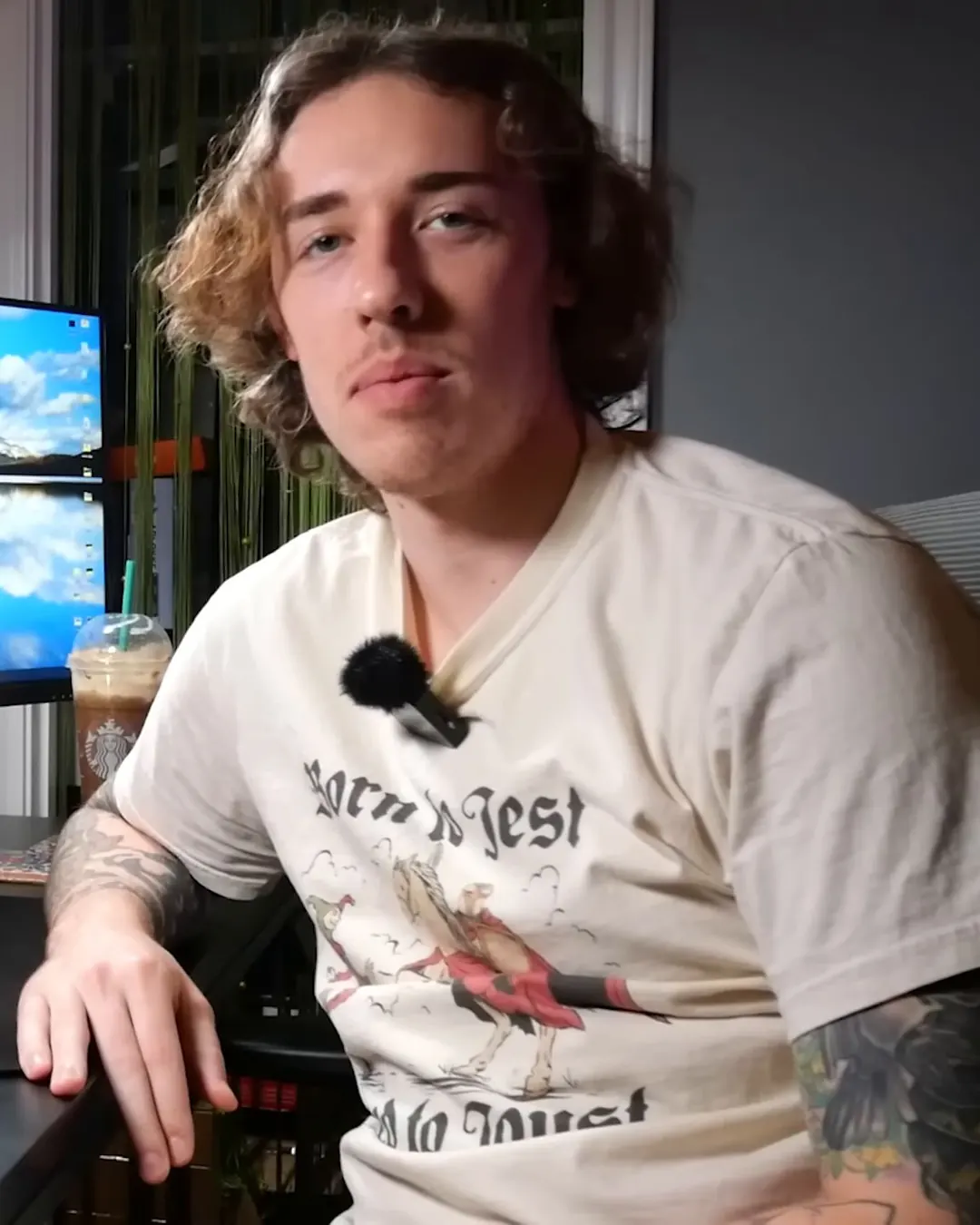 NoodleNick seated at his desk with a clip-on mic, monitors and an iced coffee behind him, looking at the camera
